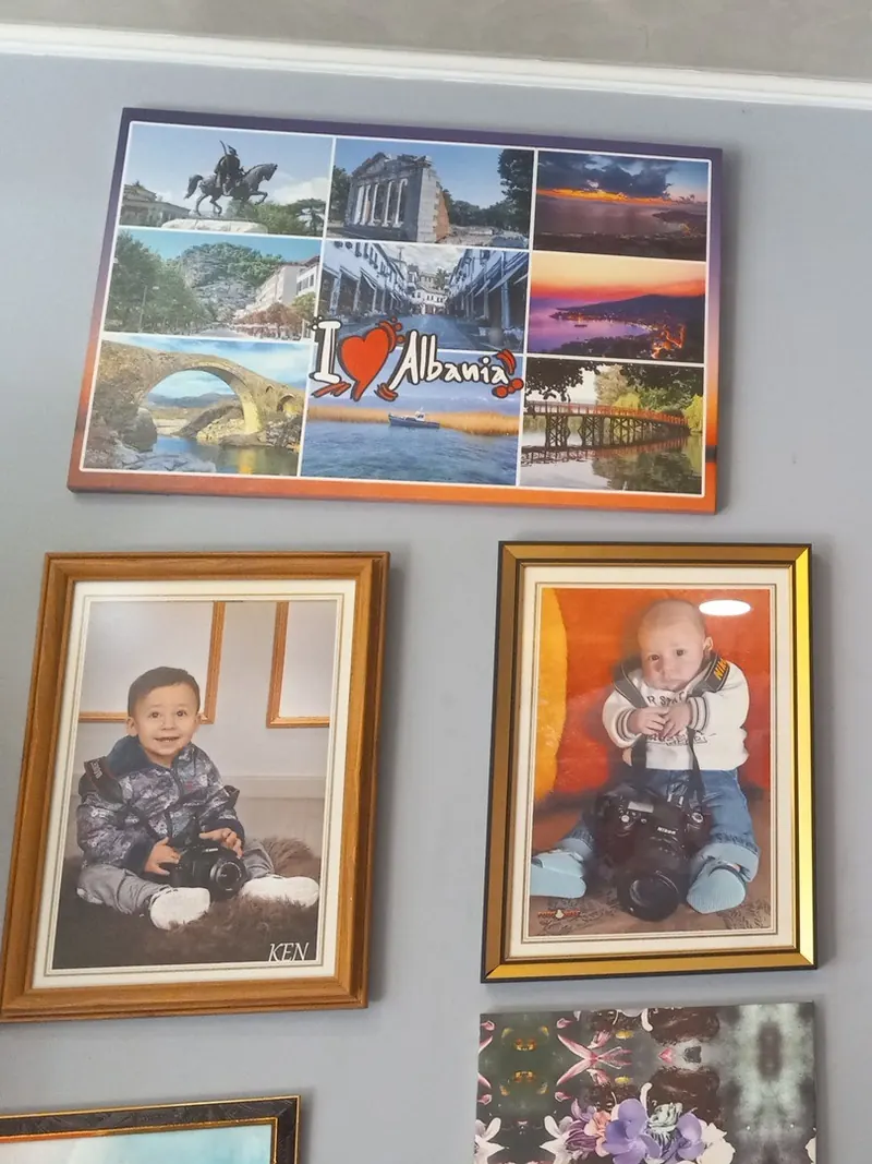 Framed children’s portraits and an Albania photo collage on the studio wall